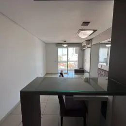 Foto de um ambiente interno com mesa de vidro e paredes brancas.