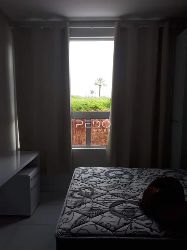 Quarto interno com janela e cortinas claras.