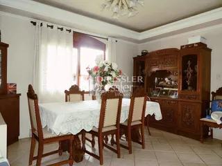Uma mesa de jantar com cadeiras e um armário de madeira são visíveis no ambiente.