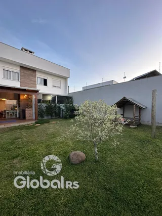 Vista externa de uma residência com jardim gramado e uma estrutura de madeira.