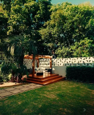 Vista de um jardim com deck de madeira e vegetação densa.