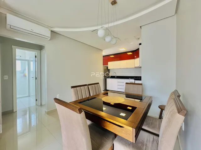 Uma sala de jantar com mesa de madeira e cadeiras em um apartamento.
