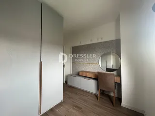 Interior de uma sala com piso de madeira e parede decorada.