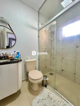 Foto de um banheiro com box de vidro e vaso sanitário branco.