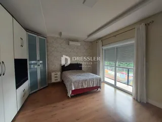 Quarto com piso de madeira e janela de grande porte em imóvel em Lajeado.