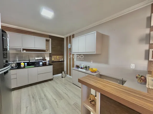 Cozinha moderna com armários brancos e piso de madeira clara.