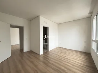 Interior de uma sala com piso de madeira clara.