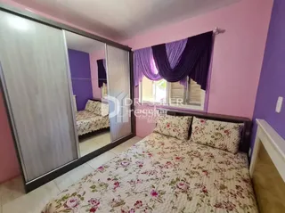 Quarto com cama e armário em ambiente com paredes rosa e roxo.