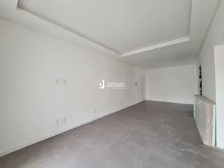 Interior de uma sala ampla com paredes brancas e piso cinza.
