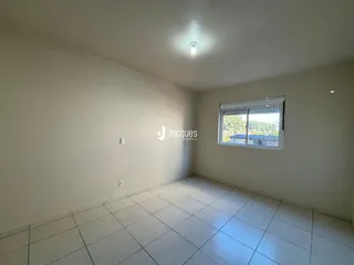 Foto interna de uma sala com piso de cerâmica clara e paredes brancas.