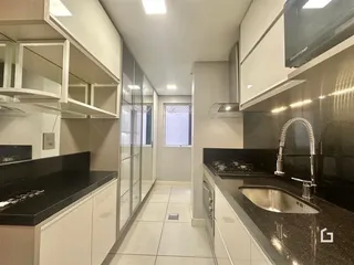 Vista da cozinha moderna com armários brancos e bancadas escuras.