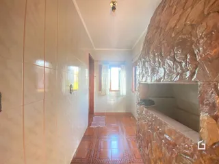 Corredor interno com piso de cerâmica e parede de pedra.