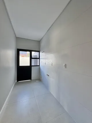Corredor interno de uma residência com paredes brancas e piso claro.