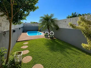 Vista externa mostrando piscina e gramado de uma propriedade.