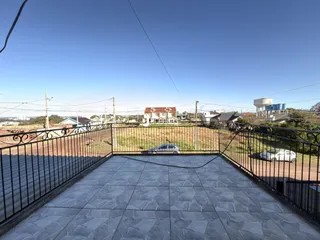 Vista de um pátio externo com piso de cerâmica e cerca de ferro.