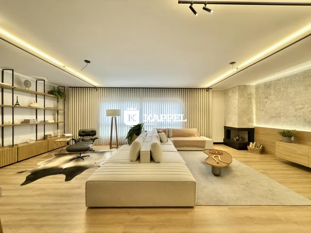 Sala de estar moderna com sofá grande e piso de madeira clara.