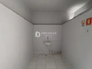 Interior de um corredor com piso de cerâmica branca e um vaso sanitário.