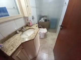 Foto de um banheiro com bancada de mármore e box de vidro.