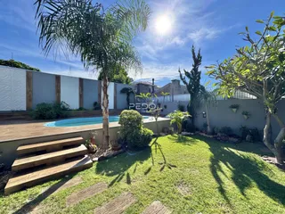 Vista externa de uma propriedade com piscina e jardim.