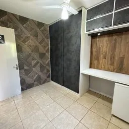 Ambiente interno com piso de cerâmica e parede texturizada em uma residência.