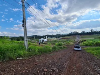 Uma estrada de terra atravessa uma área gramada com postes de energia.