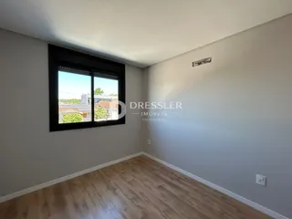 Ambiente interno de uma sala com piso de madeira e grande janela.