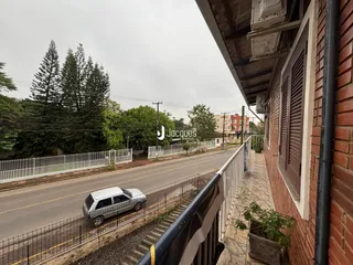 Vista lateral de uma residência com muro de tijolos e cerca ao longo de uma rua.