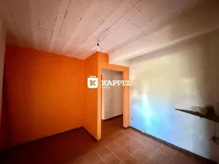 Interior de uma sala com paredes laranjas e teto de madeira exposto.