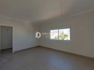 Imagem de um cômodo vazio com paredes brancas e piso de cerâmica.