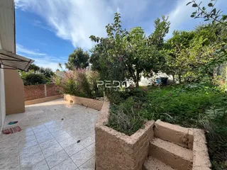 Vista externa de um pátio e jardim com muro de tijolos.