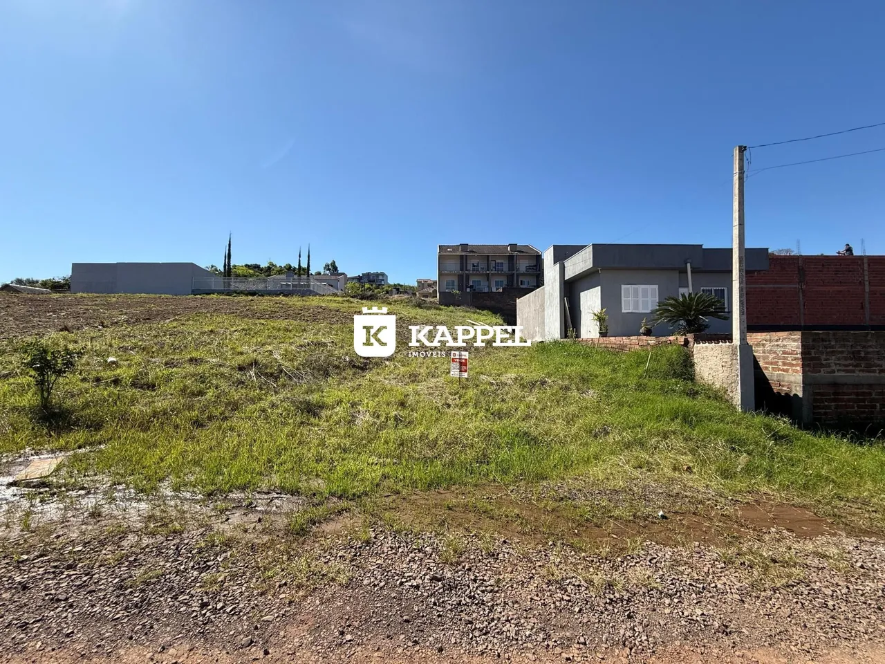 Vista externa de uma propriedade com terreno aberto e vegetação rasteira.