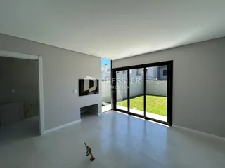 Interior de uma sala com piso de cerâmica e porta de vidro que dá para o jardim.