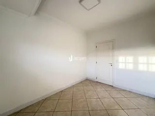 Interior de um cômodo com paredes brancas e piso de cerâmica clara.