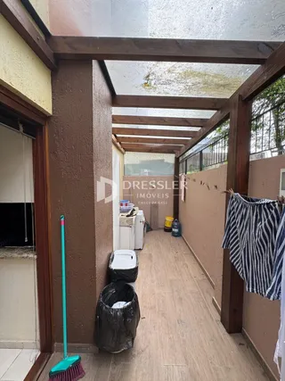 Corredor interno com estrutura de madeira e teto inclinado em uma residência.