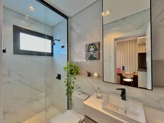 Banheiro moderno com revestimento em mármore branco e box de vidro.