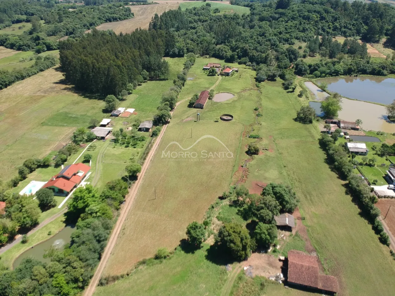 Vista aérea de uma propriedade rural com áreas verdes e corpos d'água.