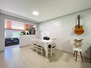 Ambiente interno de uma sala de jantar com piso de madeira clara e janela.