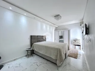 Quarto moderno com piso de mármore claro e paredes brancas.