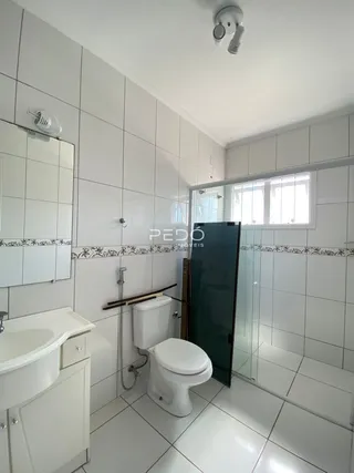 A foto mostra o interior de um banheiro com revestimento branco.