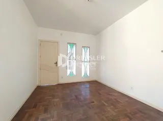 Quarto com piso de madeira e paredes brancas em uma residência.