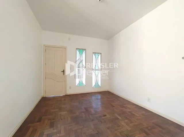 Quarto com piso de madeira e paredes brancas em uma residência.