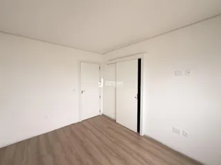 Imagem de um cômodo interno com paredes brancas e piso de madeira clara.