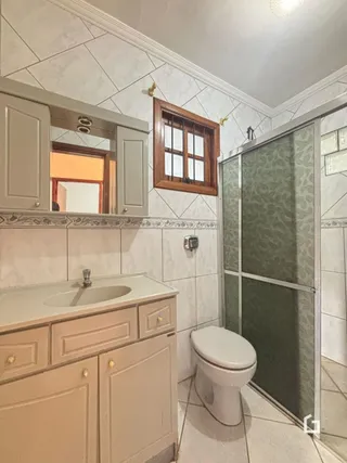 Foto de um banheiro com bancada e azulejos brancos.