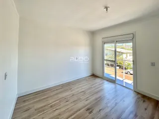 Ambiente interno com piso de madeira clara e porta de vidro voltada para o exterior.