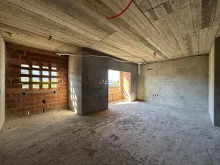 Interior de um espaço com paredes de tijolo e teto de concreto aparente.