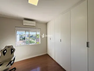 Quarto com armários brancos e piso de madeira.