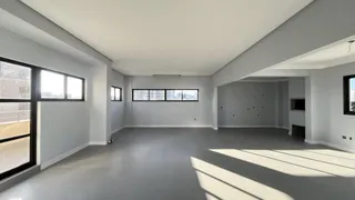 Uma sala ampla e moderna com piso de concreto e grandes janelas.