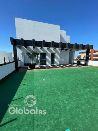 Fachada de uma residência com um pátio gramado e pérgola.