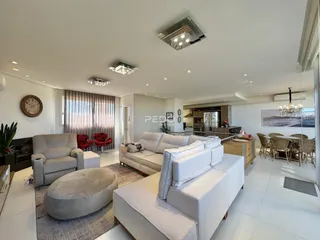 Sala de estar moderna com sofás brancos e piso claro.