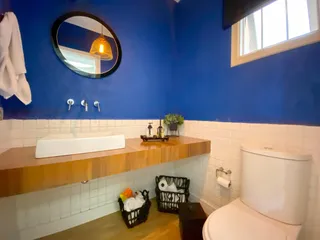 Foto de um banheiro com bancada de madeira e azulejos brancos.